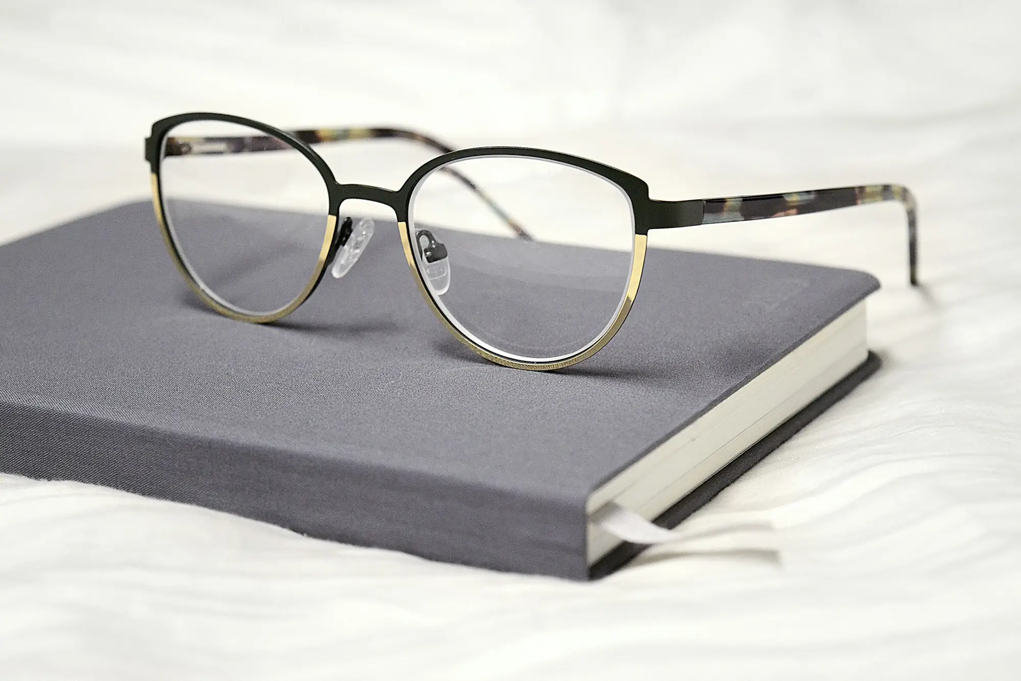 Reading glasses resting on a grey notebook