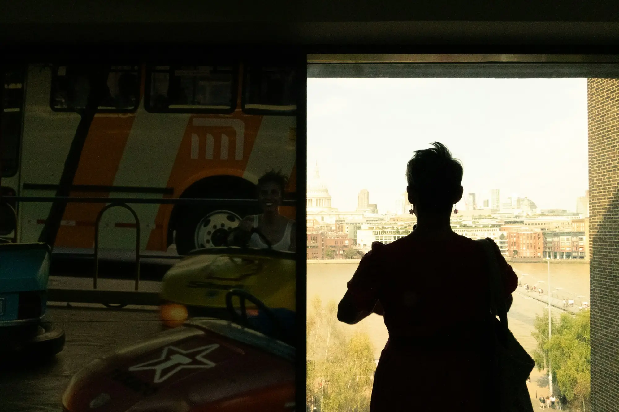 A figure at a window overlooking London at dusk